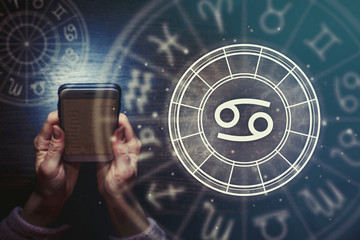 Wall Mural - female hands are holding a phone and an astrological circle with the zodiac sign cancer against the 