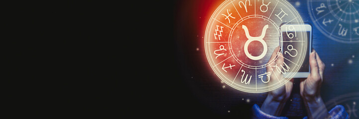 Wall Mural - female hands are holding a phone and an astrological circle with the zodiac sign taurus against the 