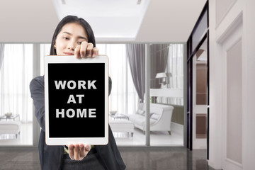 Wall Mural - Asian businesswoman showing tablet with a message for Work from home on the screen