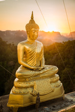 Golden Buddha Statue In Thailand At Sunset With Mountains Landscape In The Background