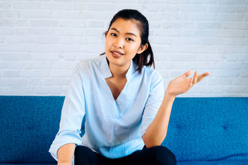 Wall Mural - Happy friendly Asian woman looking at camera and talking, making video call conference, online job interview at home. Millennial female internet teacher tutor and vlogger on the job.