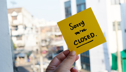 hand holding yellow sticky note	