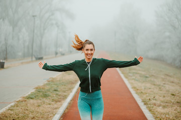 Wall Mural - Beautiful girl with ponytail is running outdoors on foggy morning.