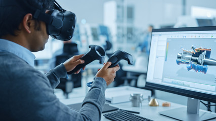 Leinwandbilder - Modern Industrial Factory: Mechanical Engineer Wearing Virtual Reality Headset, Holding Controllers, Uses VR technology for Industrial Design, Development and Prototyping in CAD Software on Computer.