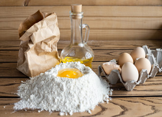 Olive oil, flour and eggs on a wooden kitchen table