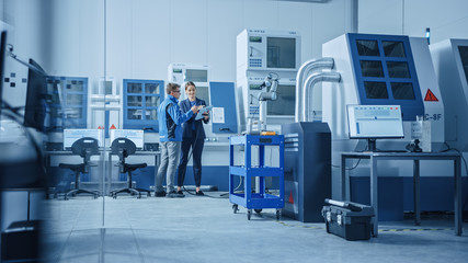 Aufkleber - Modern Factory: Female Project Manager and Male Engineer Standing, Talking and Using Tablet Computer for Programming Robot Arm Assembly Line. Contemporary Facility with High Tech CNC Machinery