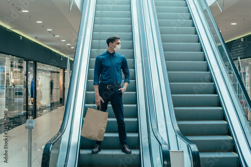 lone man in a protective mask standing on the escalator steps Tableau sur Toile