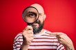 © Krakenimages.com - Handsome detective bald man with beard using magnifying glass over red background with surprise face pointing finger to himself