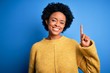 © Krakenimages.com - Young beautiful African American afro woman with curly hair wearing yellow casual sweater showing and pointing up with finger number one while smiling confident and happy.