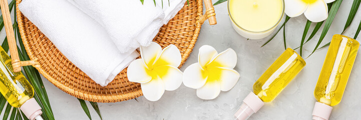 Wall Mural - Spa massage Aromatherapy body care background. Spa herbal balls, cosmetics, towel and tropical leaves on gray concrete table. Top view, flat lay, overhead, web banner. Beauty and health care concept