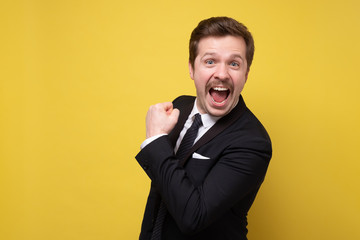 Sticker - Happy businessman with funny mustache fists gesturing, isolated on yellow wall.