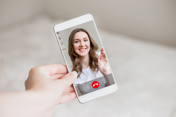 A female hand holds a mobile phone with a girl on the screen, video chat. A woman makes a video call to her friend. Happy young girl smiles on a phone screen, interface, call buttons