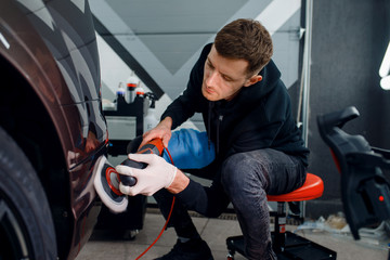 Wall Mural - male worker polishes bumper, car detailing