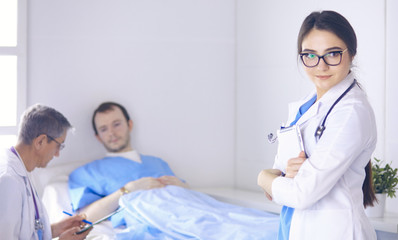 Wall Mural - Doctor checking heart beat of patient in bed with stethoscope