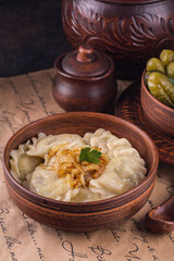 Wall Mural - Russian Vareniky  - dumplings, pickles. Vareniky filled with potato and mushrooms, served with fried onion. Homemade. Background - cyrillic text (russian poem by  A. Pushkin)