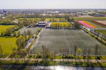 Tulipfields in full blossom from above in Holland next to a soccer field