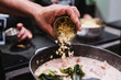 © REMEDIOS PUERTA/ADDICTIVE STOCK - Crop chef spilling fresh ingredient into pan with stew while preparing dinner during cooking lesson in restaurant in Navarre, Spain