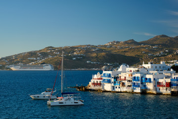 Sunset in Mykonos island, Greece with yachts in the harbor and colorful waterfront houses of Little Venice romantic spot on sunset and cruise ship. Mykonos townd, Greece