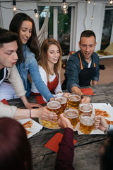 Wall Mural - Group of friends toasting with a glass of beer while eating pizza - Millennials have fun together - Day of happiness between young men and women