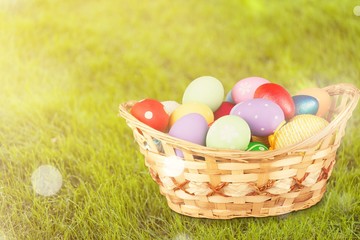 Wall Mural - Colored easter eggs in the basket on the green grass