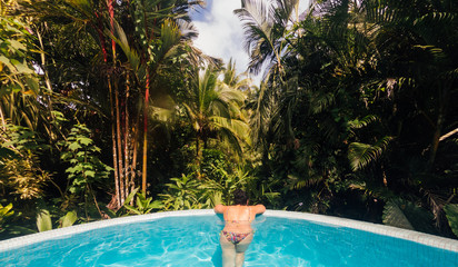 Young woman relaxes by bathing in an infinity pool at a luxurious Costa Rica resort