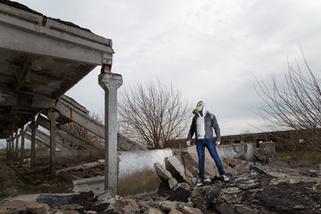 Human in gas mask standing among ruins and dramatic sky background. Enviromental pollution, ecology disaster, radiation, biological hazard concept.