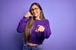 © Krakenimages.com - Young beautiful smart woman wearing glasses over purple isolated background smiling doing talking on the telephone gesture and pointing to you. Call me.