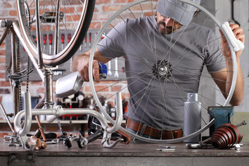 Wall Mural - man repair the vintage bicycle in garage workshop on the workbench with tools, diy concept