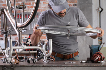 Wall Mural - man repair the vintage bicycle in garage workshop on the workbench with tools, diy concept