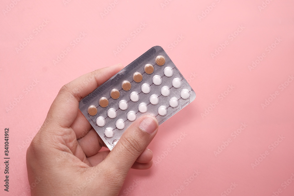 women hand holding birth control pills on pink. - obrazy, fototapety, plakaty 