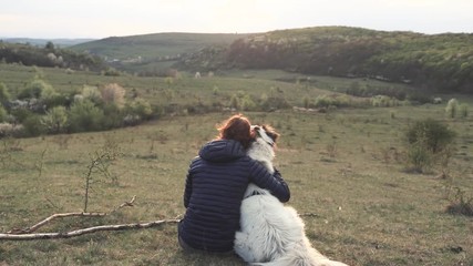 Wall Mural - woman petting her white dog outdoors at sunset