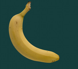 Single yellow banana isolated on green background.