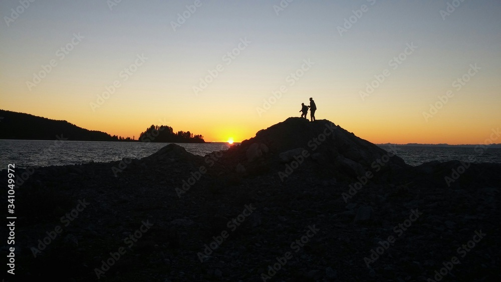 Silhouette People Overlooking Calm Sea At Sunset - obrazy, fototapety, plakaty 