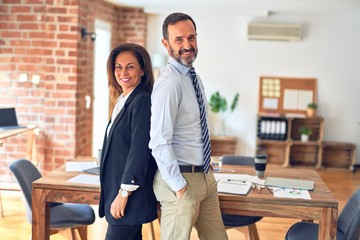 Two middle age business workers standing working together in a meeting at the office with a happy and cool smile on face. Lucky person.