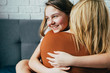 people and family concept - happy smiling girl with mother hugging on sofa at home.Happy mother's day! Mom and her daughter child girl are hug. Family holiday and togetherness