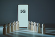 © oleg_chumakov - Mobile generation. Network connecting technology. Modern smartphone with 5G inscription, wooden figures. Copy space