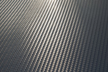 Bended Surface Of Grey Woven Carbon Fibre Composite Sheet.