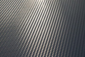 Bended surface of grey woven carbon fibre composite sheet.