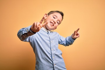 Sticker - Young little boy kid wearing elegant shirt standing over yellow isolated background smiling looking to the camera showing fingers doing victory sign. Number two.