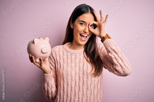 Fotografía Young beautiful brunette woman holding piggy bank saving money for retirement wi