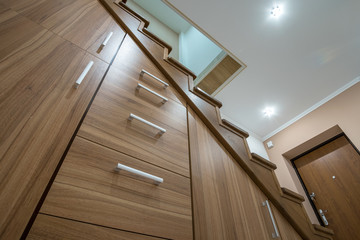 Sticker - Modern architecture interior with luxury hallway with glossy wooden stairs in multi-storey house. Custom built pullout cabinets on glides in slots under stairs. Use of space for storage.