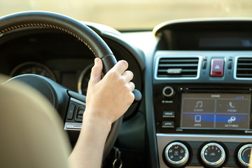 Canvas Print - Close up view of woman hands holding steering wheel driving a car on city street on sunny day.