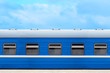 © ANGHI - Blue passenger railway wagon on the platform, blue sky in the background
