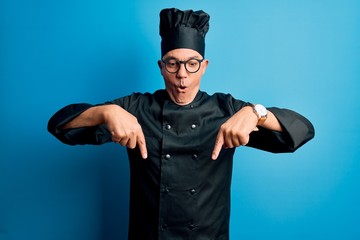 Poster - Middle age handsome grey-haired chef man wearing cooker uniform and hat Pointing down with fingers showing advertisement, surprised face and open mouth