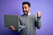 © Krakenimages.com - Young handsome businessman with beard working using laptop over purple background screaming proud and celebrating victory and success very excited, cheering emotion