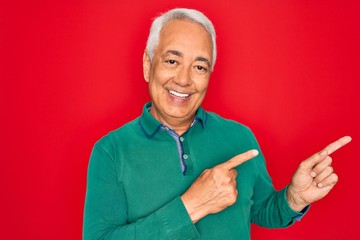 Poster - Middle age senior grey-haired man wearing casual sweater over red isoalted background smiling and looking at the camera pointing with two hands and fingers to the side.