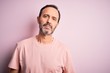 Middle age hoary man wearing casual t-shirt standing over isolated pink background Relaxed with serious expression on face. Simple and natural looking at the camera.
