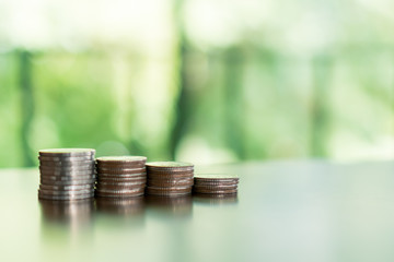 Gold coins on table and green nature bokeh background.