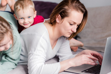 Wall Mural - Young women works at home with laptop along with two children.Children want to communicate with mother, make noise and interfere with work.Self-isolation during coronovirus pandemic