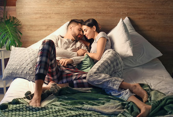 Wall Mural - Happy young couple resting on bed at home